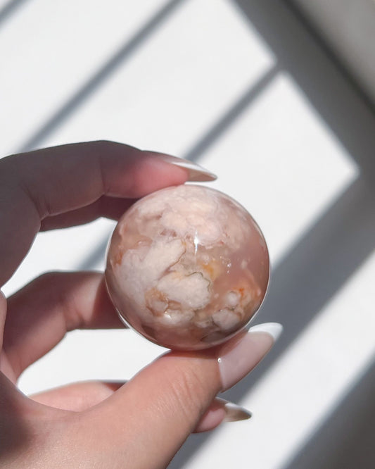 Close-up of Sphere 11 held under natural sunlight, showing cloud-like formations and peachy tones
