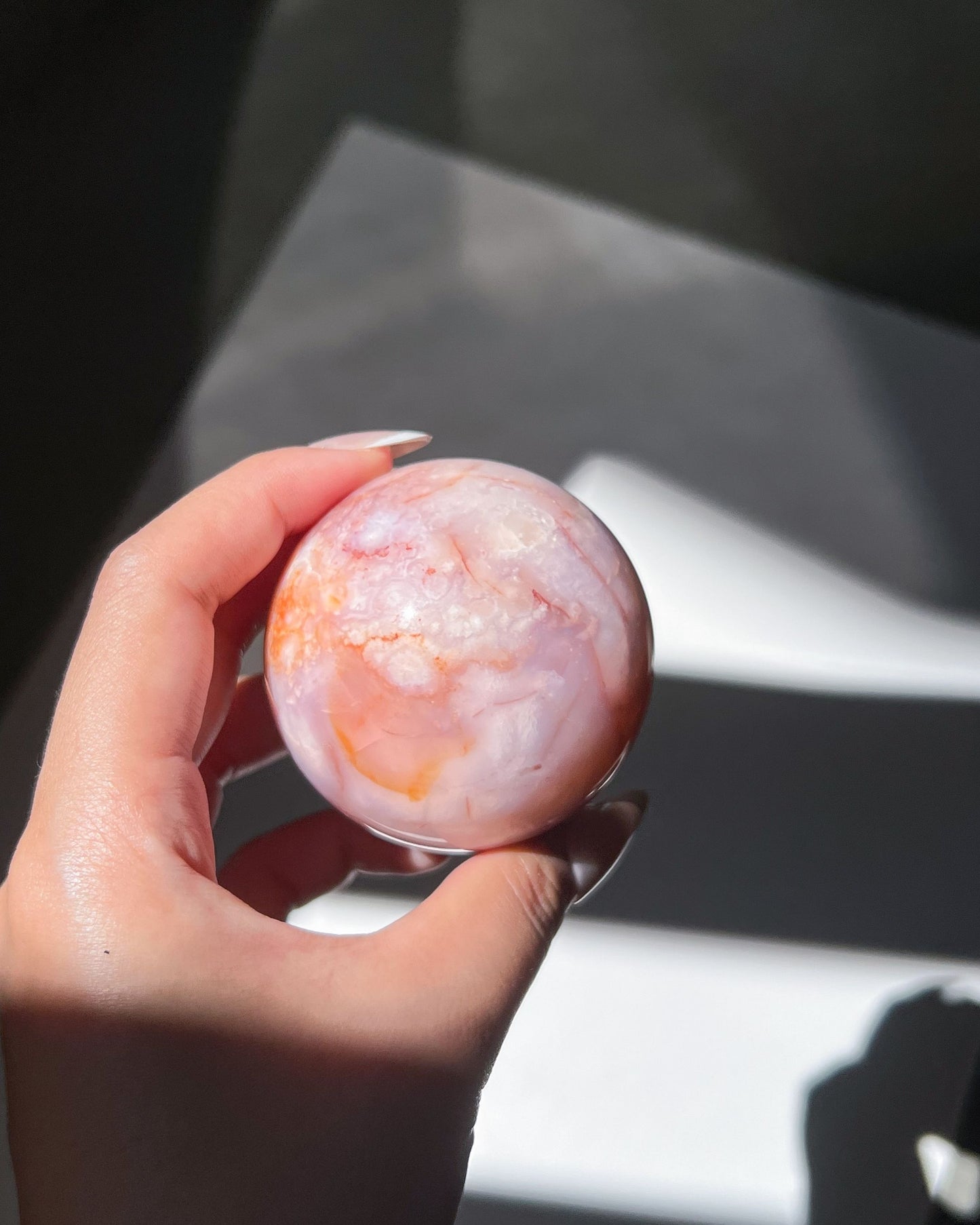 Pastel-toned sphere in bright sunlight revealing light white plumes and gentle opacity.