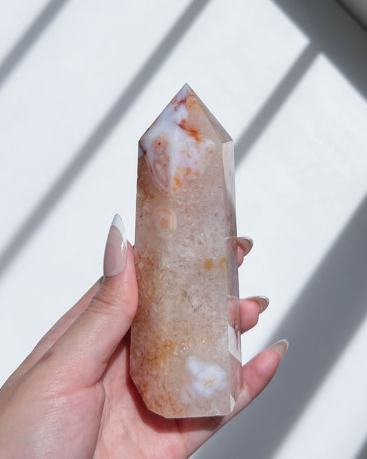 Front view of the crystal tower under sunlight, highlighting translucent clarity and daisies.