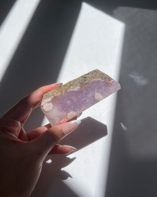 Hand holding back view of Leia crystal slab showing quartz ridge and white floral plumes