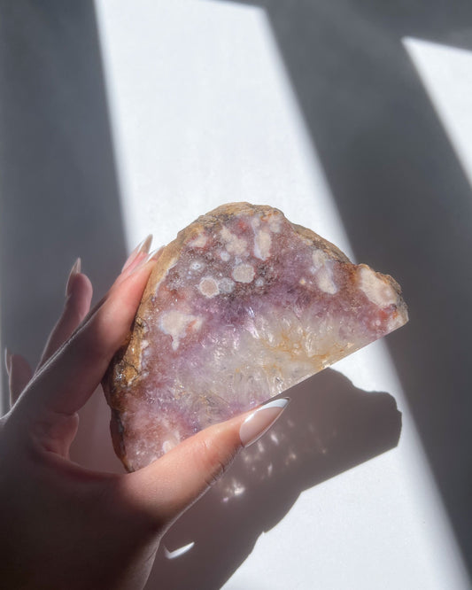 Hand holding Avery slab showing golden quartz base and lavender-pink floral inclusions
