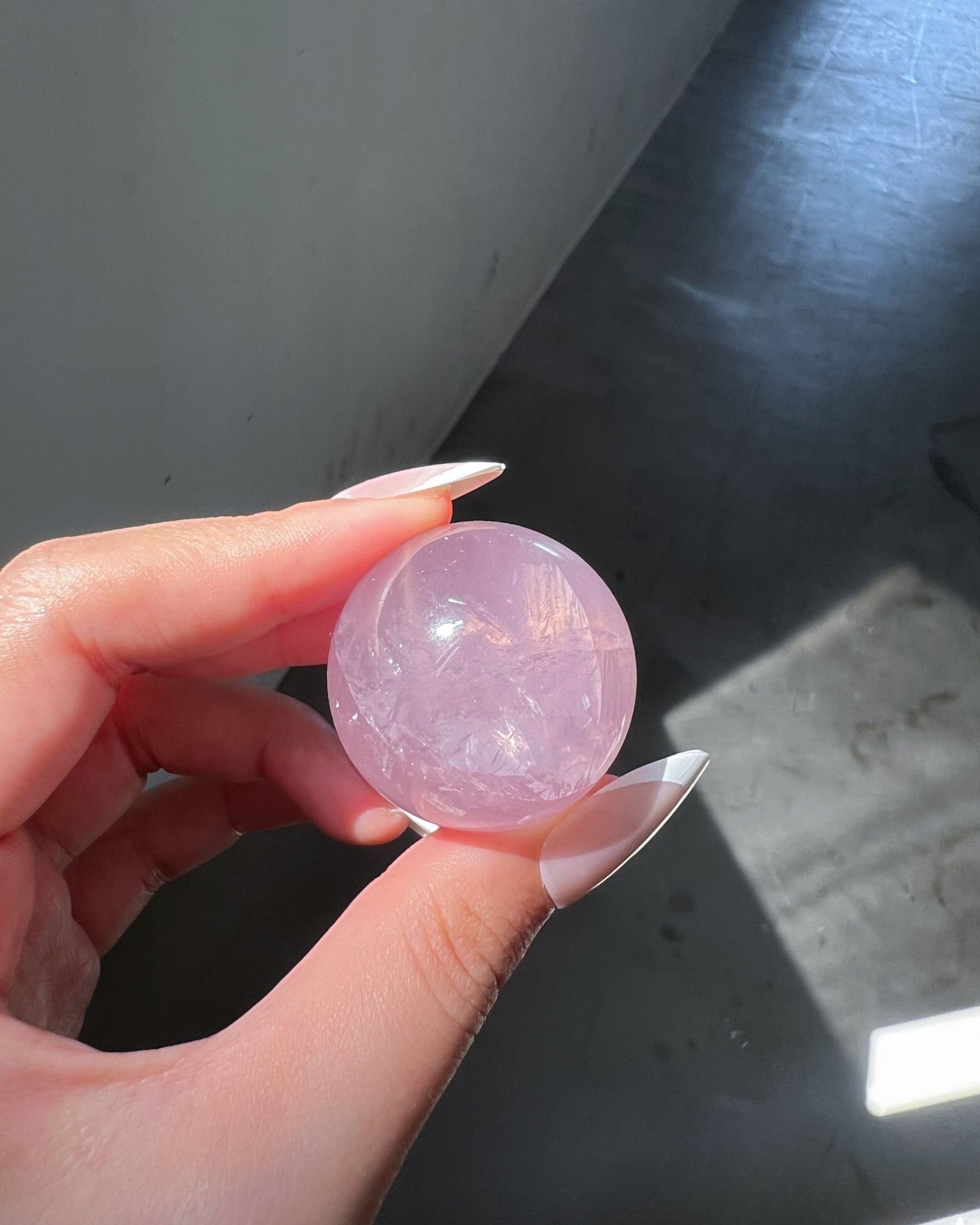 Rose Quartz Crystal ball illuminated under direct sunlight, revealing fibrous internal veils, glow and subtle pink hue