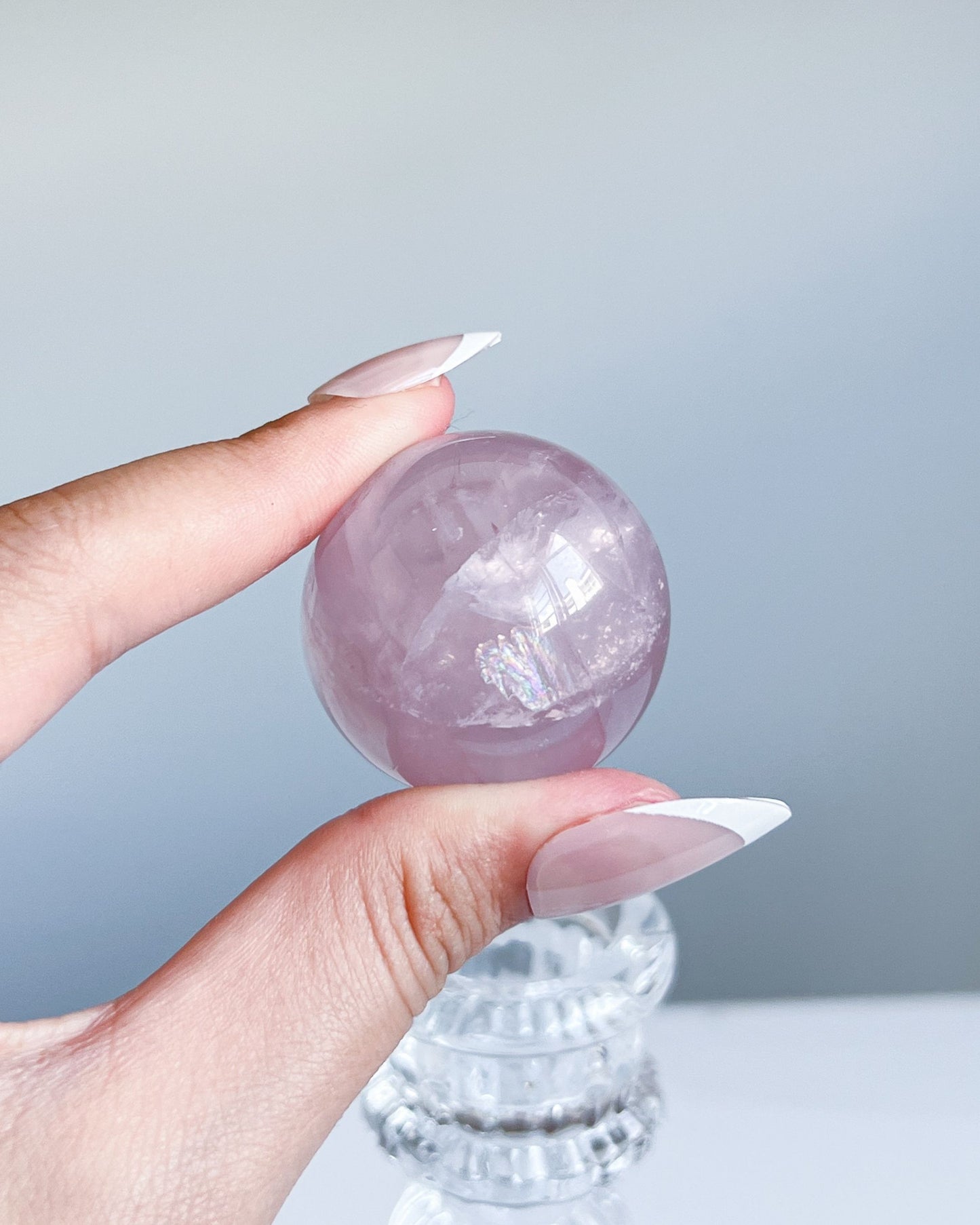Hand holding Girasol Rose Quartz sphere G with visible inner rainbow sheen and silky textures