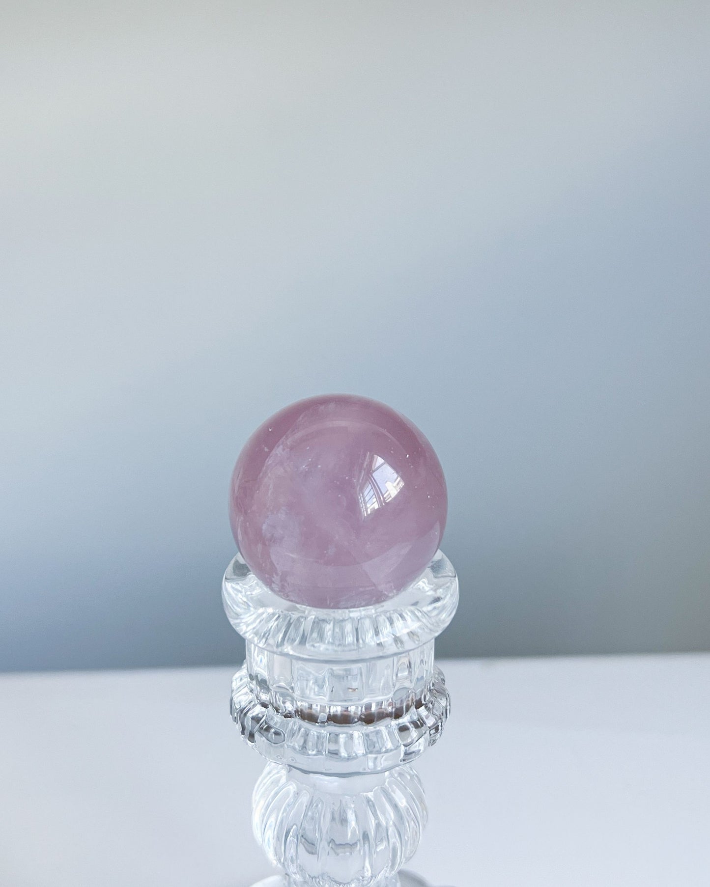 Girasol Rose Quartz sphere G styled on faceted glass stand against clean minimal background