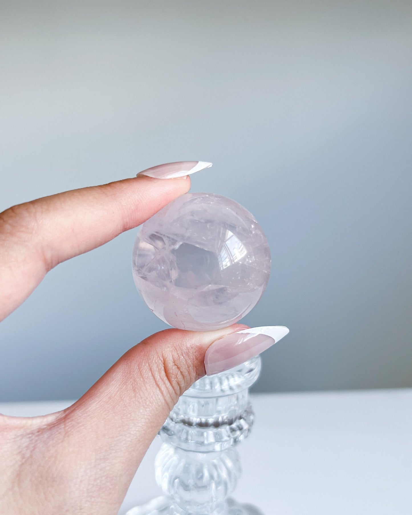 Side angle of Girasol Rose Quartz Sphere I with natural daylight, showing misty translucence and smooth surface
