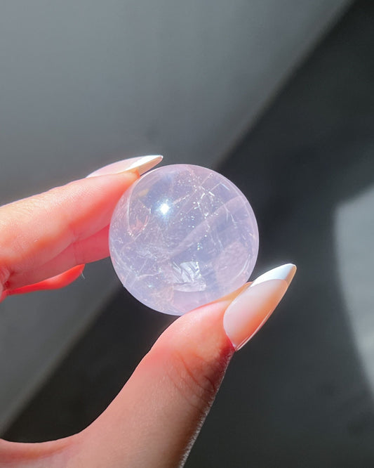 Close-up of Girasol Rose Quartz sphere glowing under direct sunlight, showing layered clarity and inner shimmer