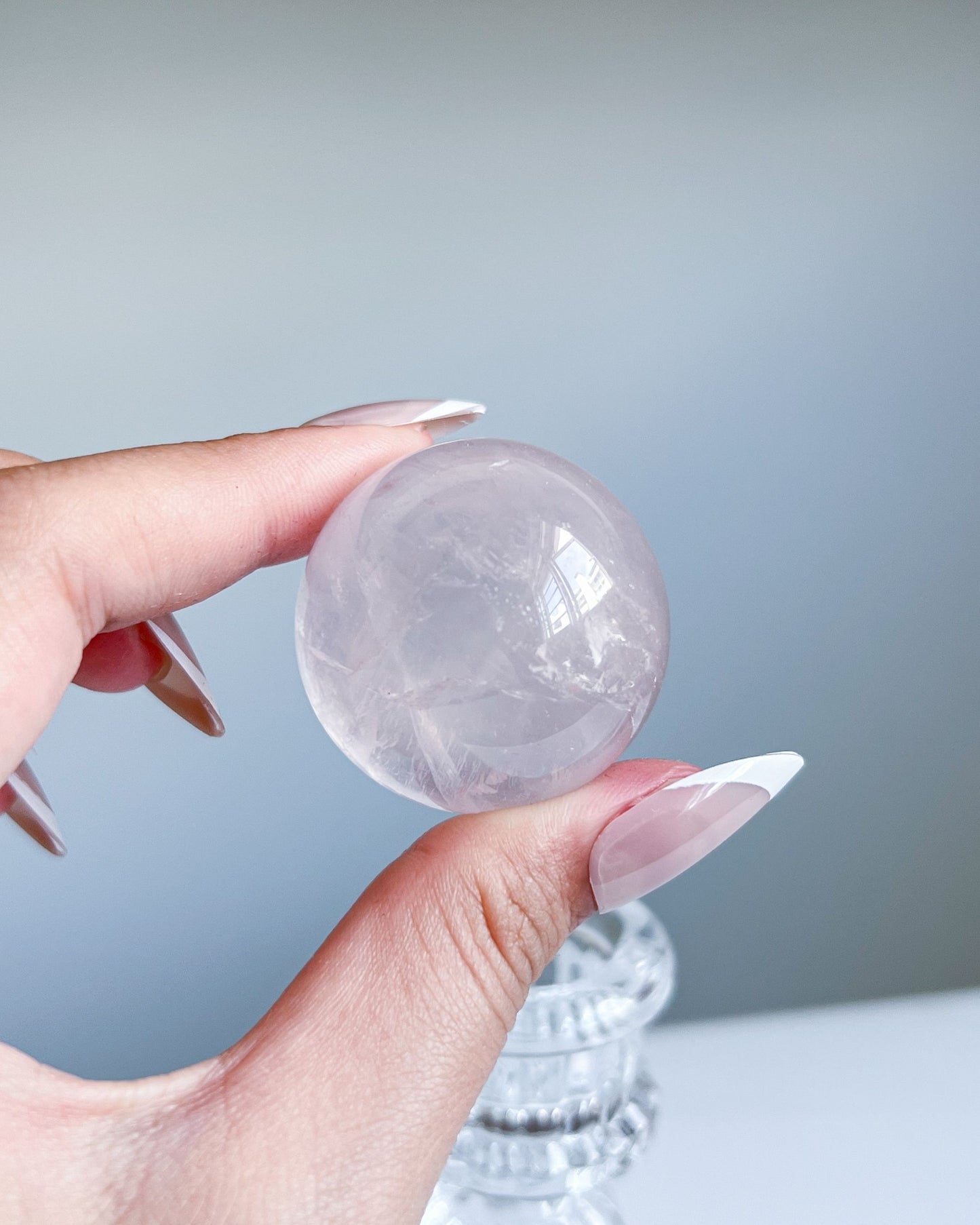 Girasol Rose Quartz sphere held in hand with soft daylight bouncing off the glassy surface