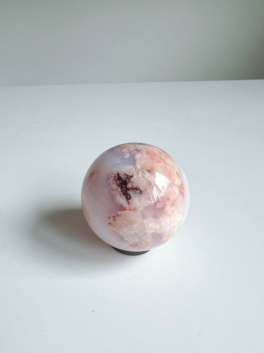 Side angle of a Carnelian Flower Agate sphere showing the 'K', delicate peach clouds and grounding reddish mineral formations