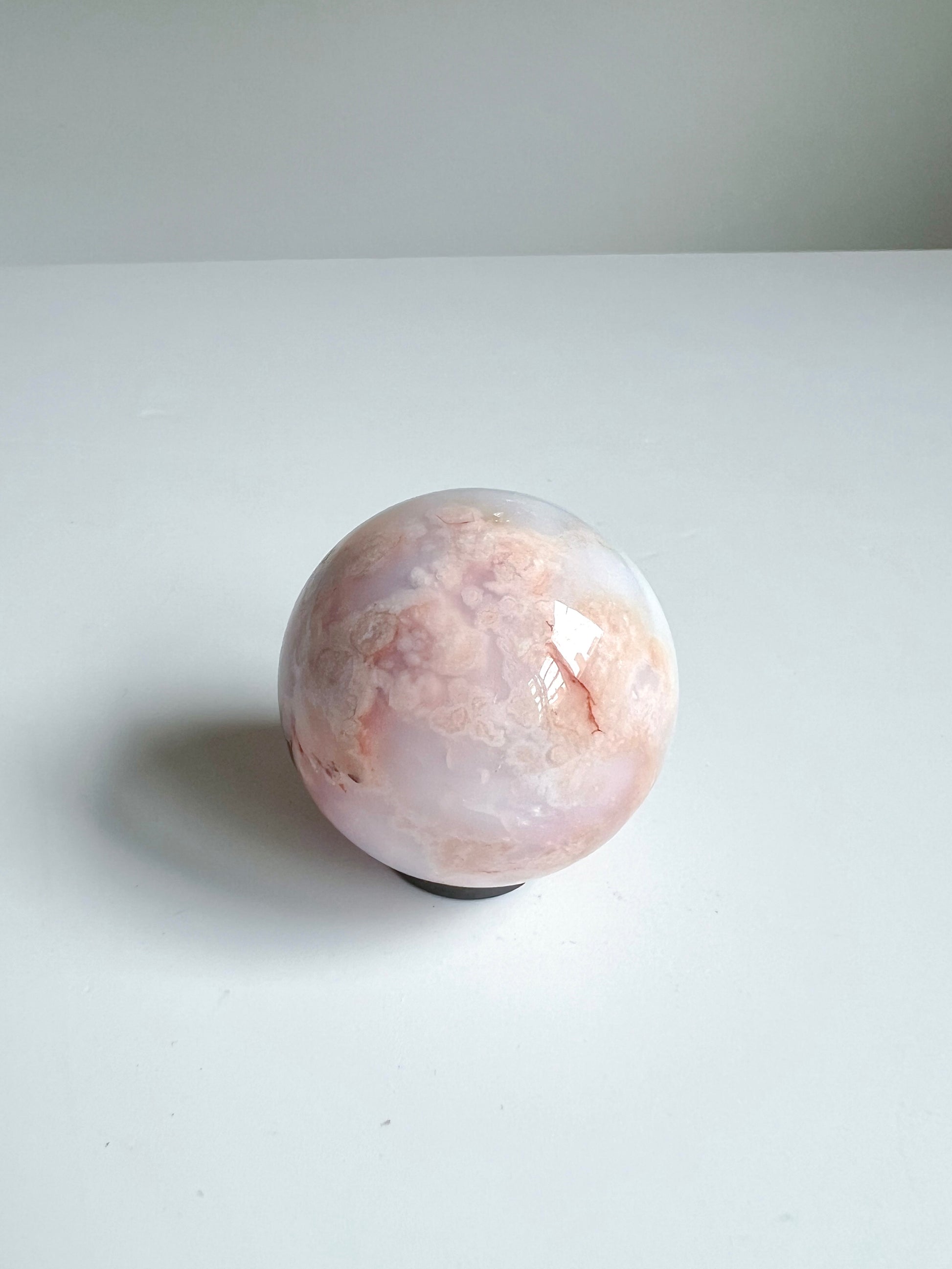 Close-up of the crystal sphere’s gentle petal-like texture with warm, misty layers in blush, cream, and coral tones.