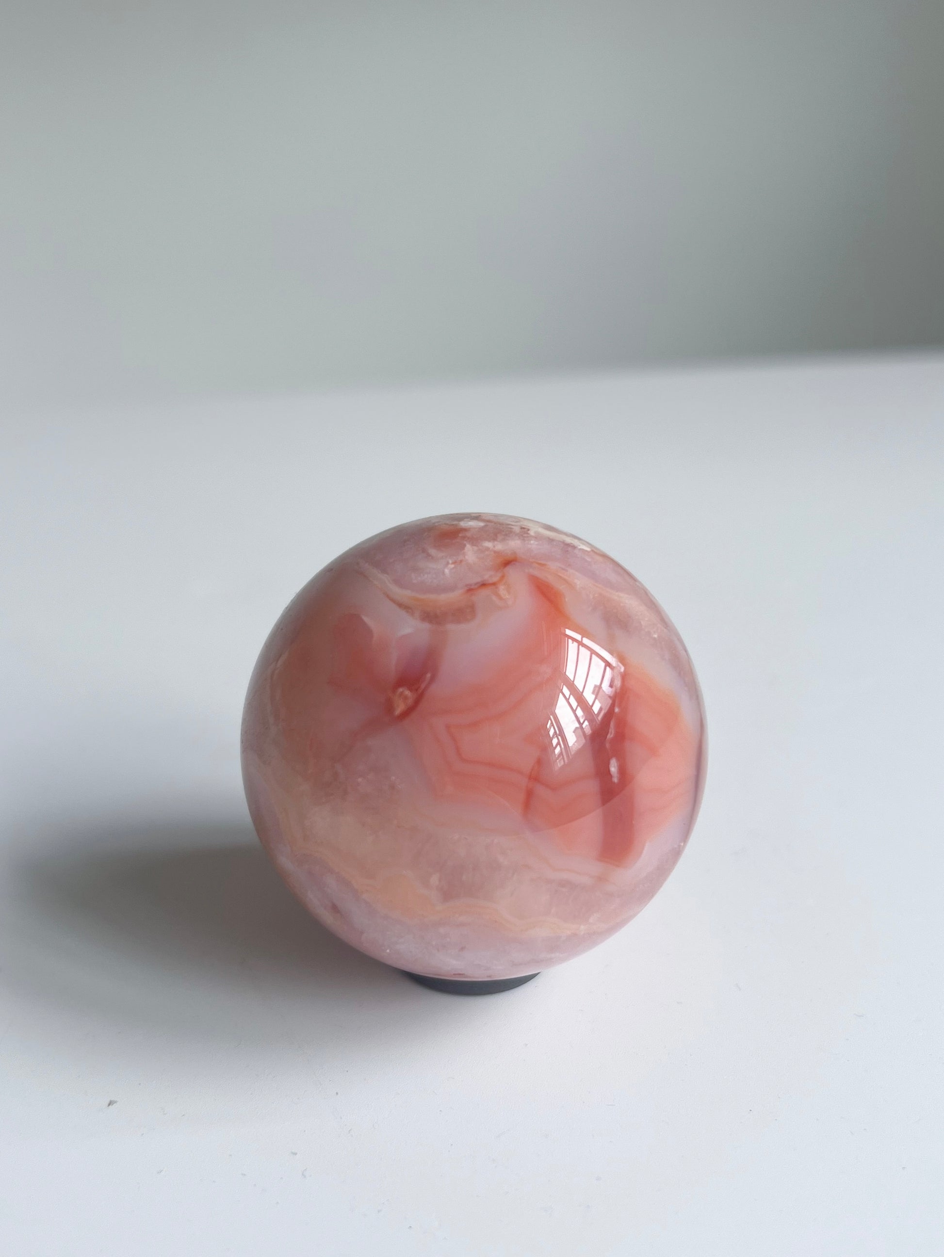 Radiant Carnelian Flower Agate sphere glowing with coral bands and creamy layers — a spark of joy and warmth.