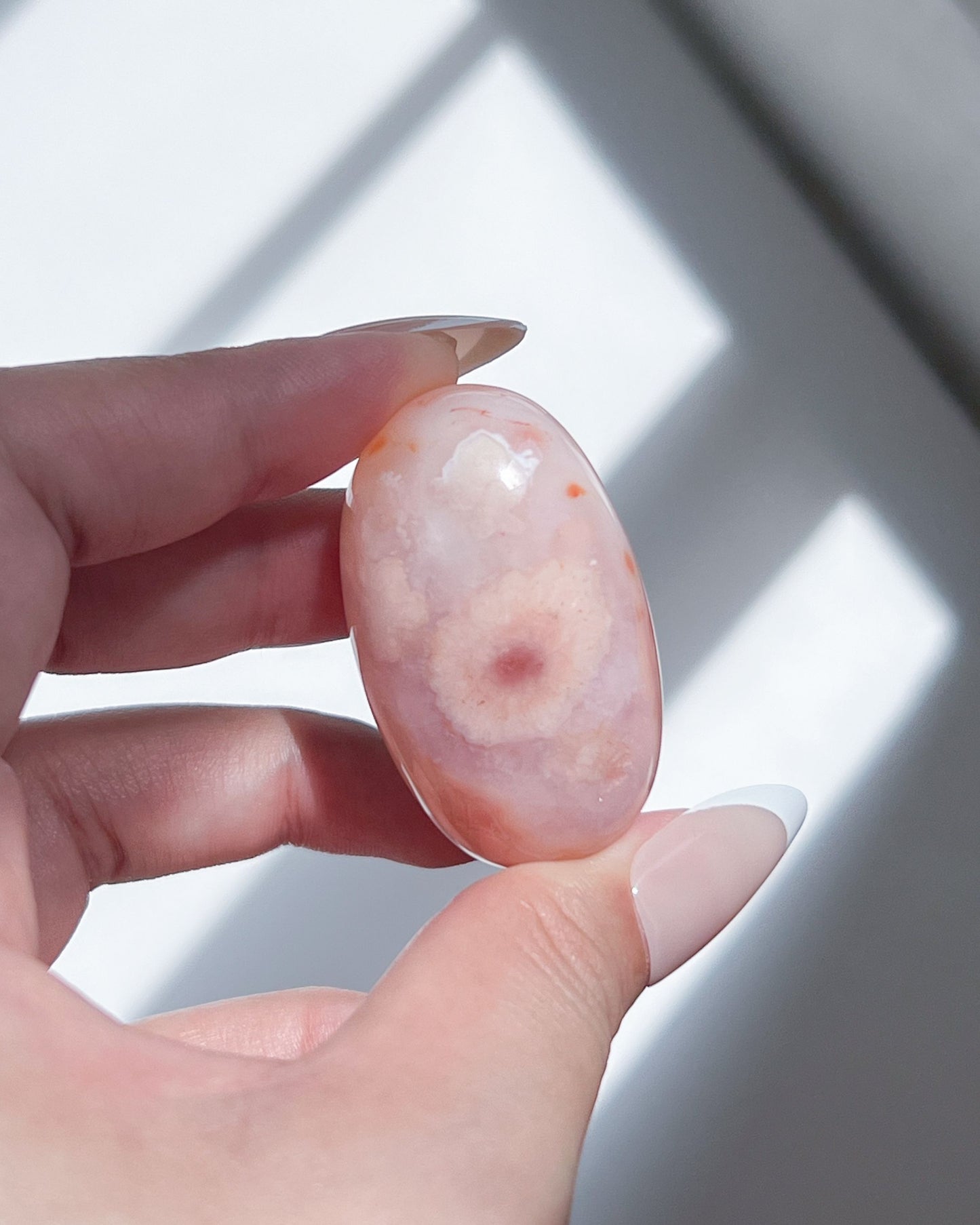 Handheld Carnelian Flower Agate bean featuring a prominent flower bloom motif in warm blush and soft peach.