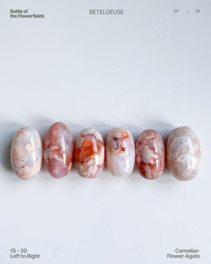 Row of Carnelian Flower Agate beans (15–20) in dreamy pastel and orange tones under daylight – left to right view