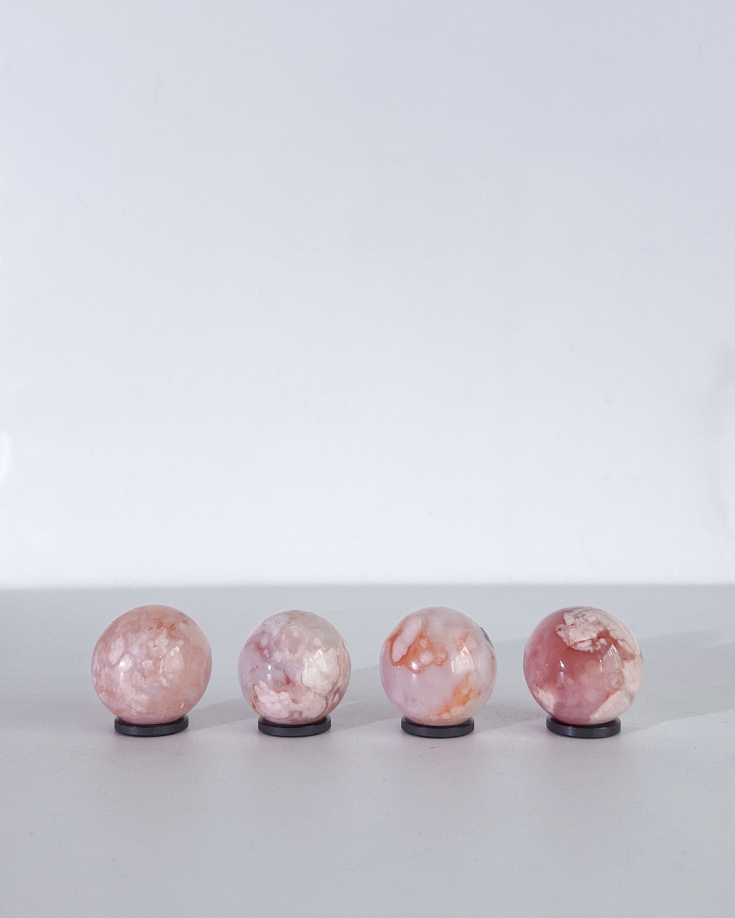 Rear view of Carnelian Flower Agate spheres revealing cloudy banding and delicate plume patterns in soft natural tones