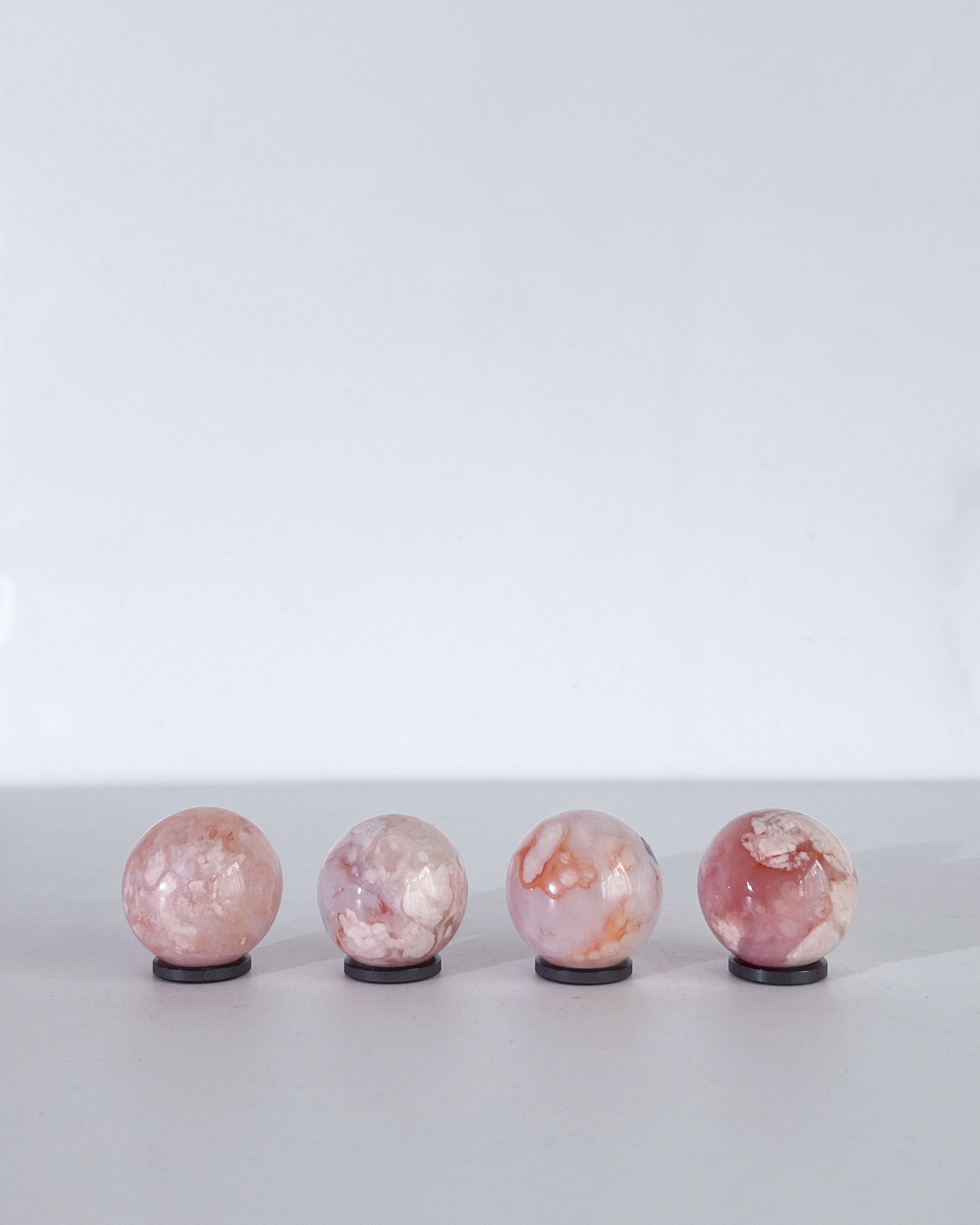 Rear view of Carnelian Flower Agate spheres revealing cloudy banding and delicate plume patterns in soft natural tones