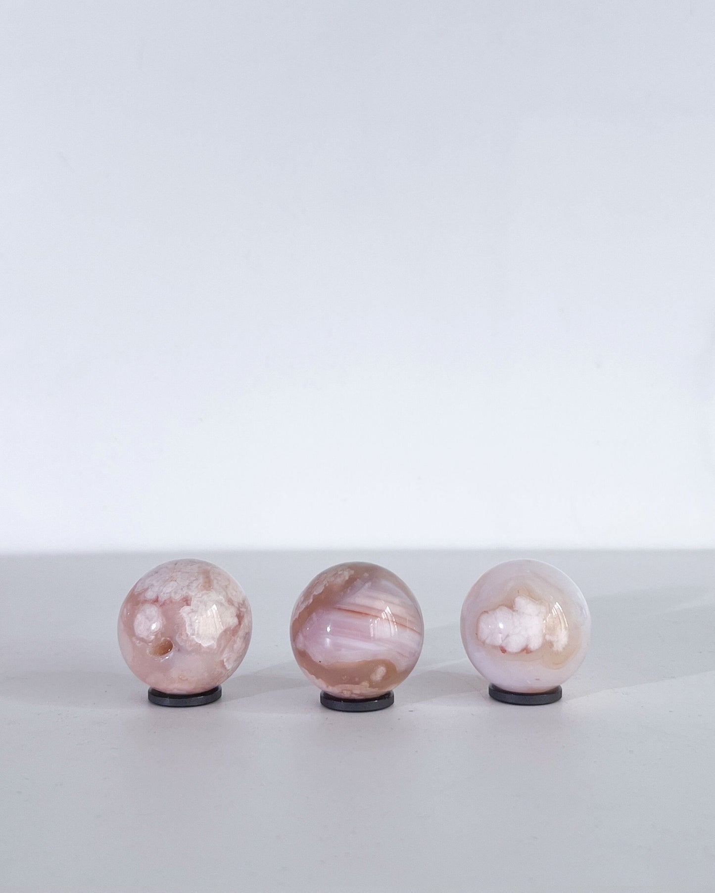 Back view of the same three Carnelian Flower Agate spheres, highlighting their soft translucency, layered banding, and unique cloud-like formations.