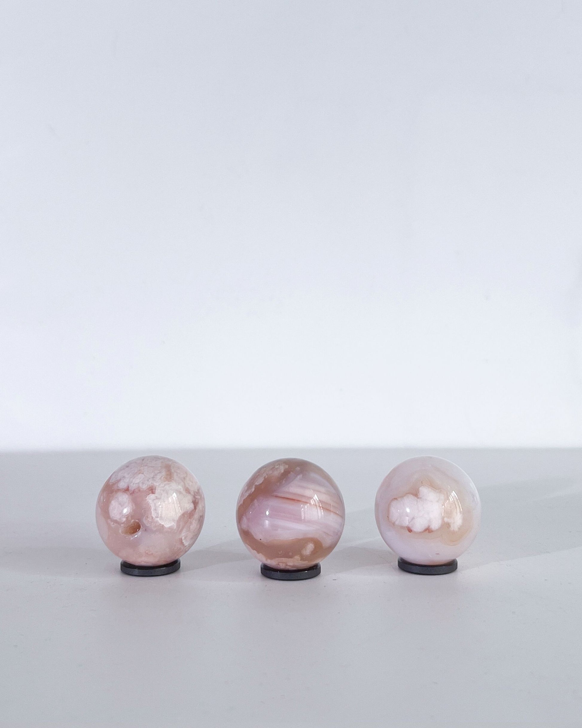 Back view of the same three Carnelian Flower Agate spheres, highlighting their soft translucency, layered banding, and unique cloud-like formations.