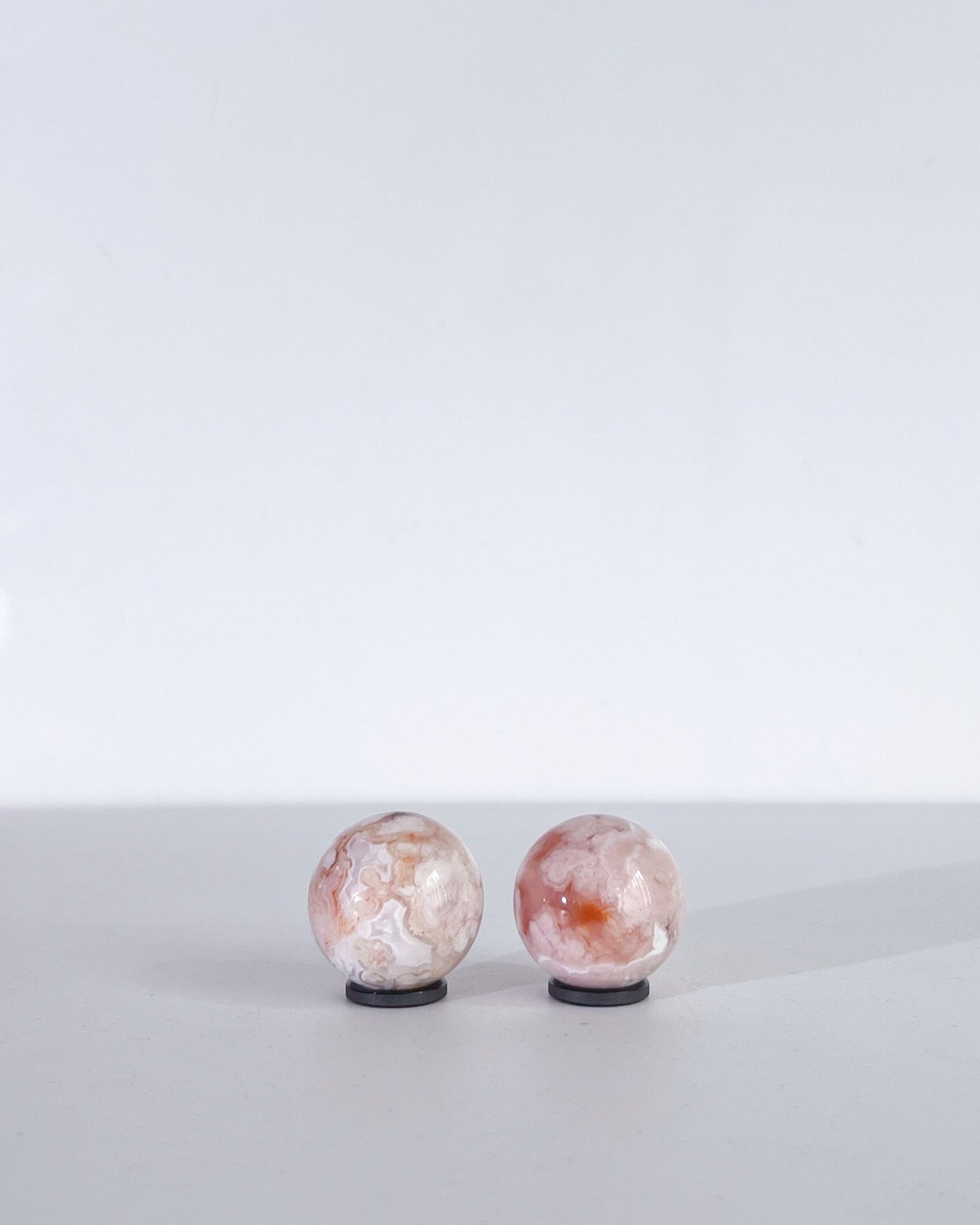 Front-facing view of Carnelian Flower Agate spheres 08–09, highlighting their bright plumes and milky patterns.