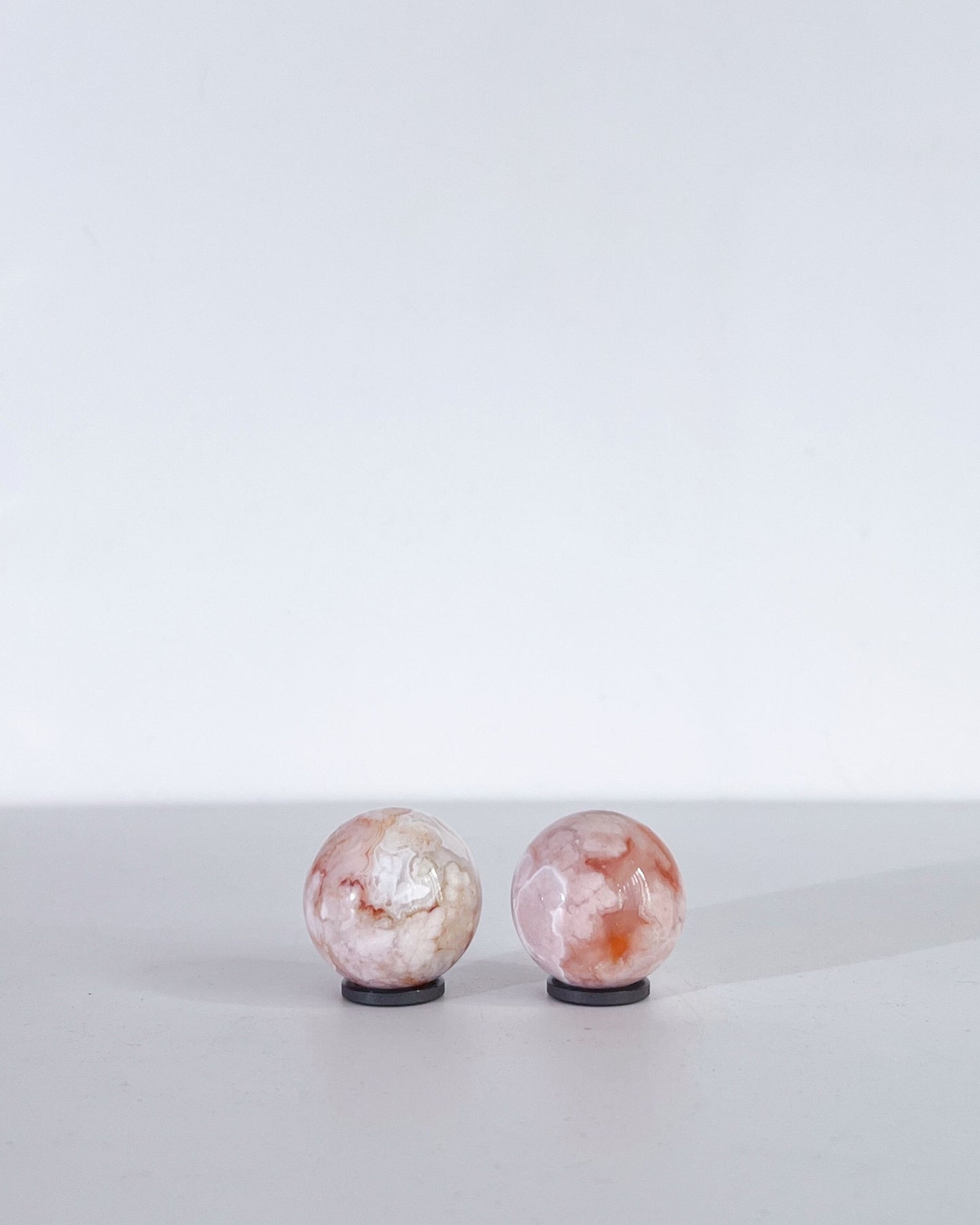 Top-down view revealing the organic floral-like textures of both Carnelian Flower Agate spheres.
