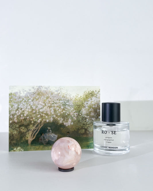 Carnelian Flower Agate Sphere 10 Suki styled with perfume bottle and floral art card under soft lighting