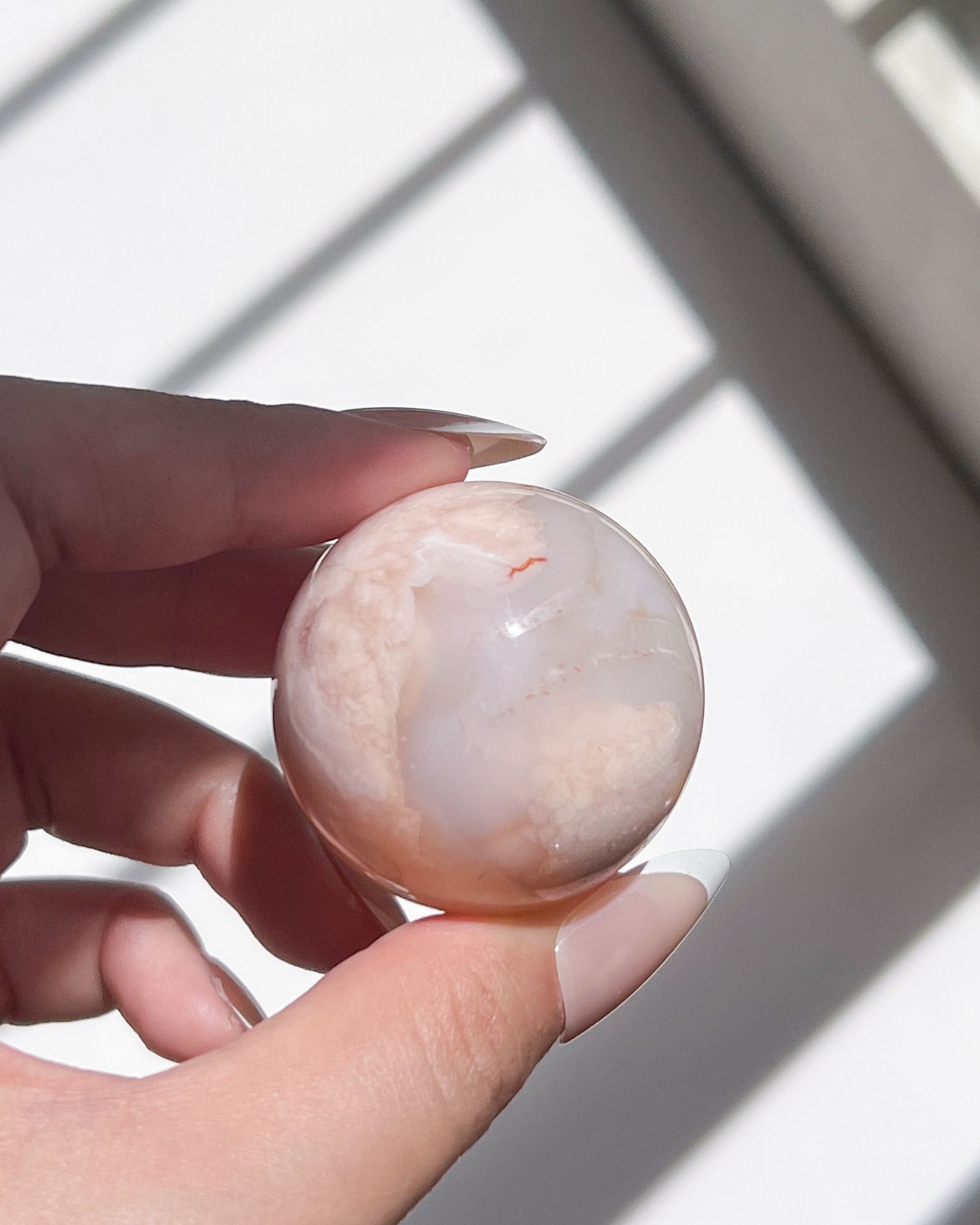 Holding Sphere 10 Suki with light shadows showing cream and blush tones with visible red vein