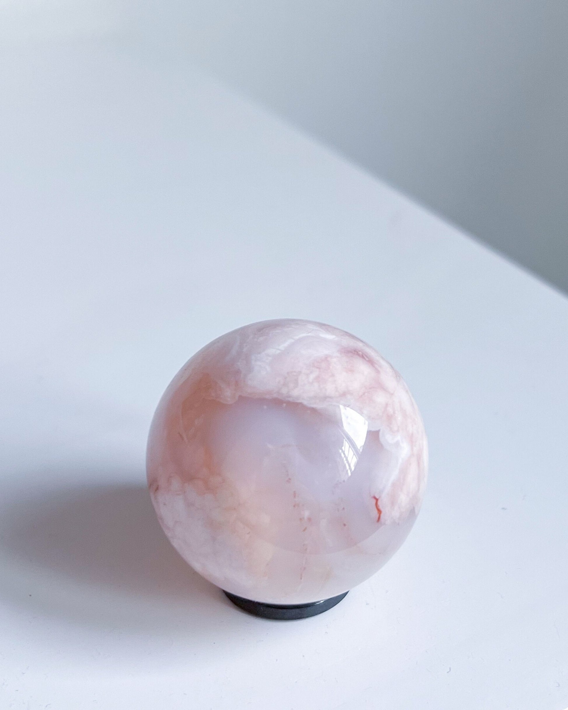 Sphere 10 Suki placed on white surface, glowing softly with pink and ivory inclusions