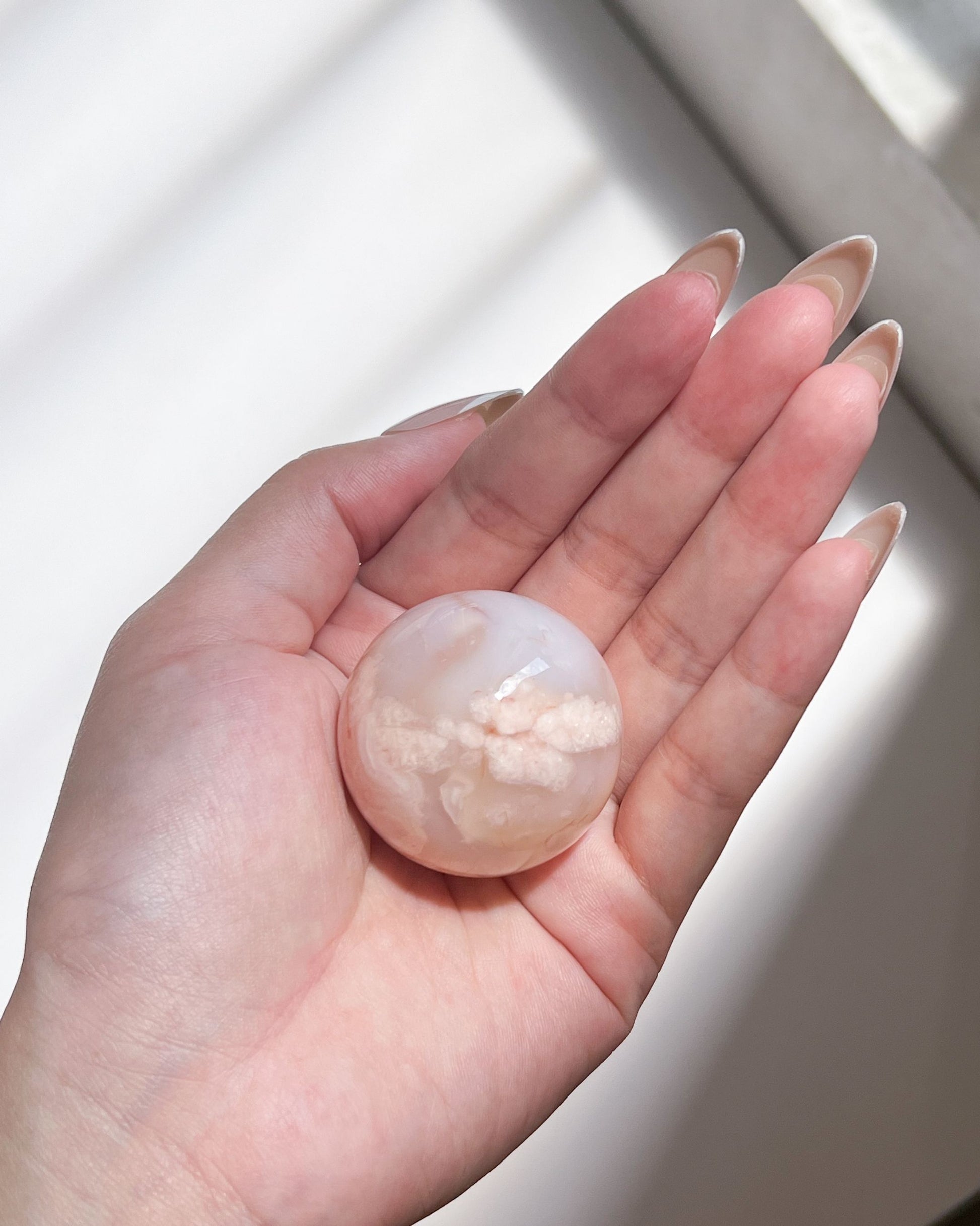 Sphere 10 resting on open palm in daylight, showing delicate color transitions and natural texture