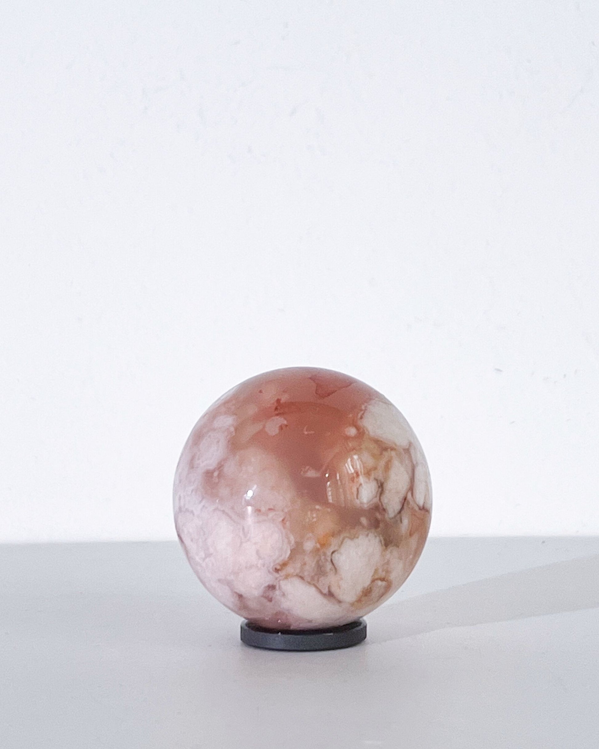 Left side of Sphere 11 with soft white florals set in a pinkish amber base, against a minimal white wall