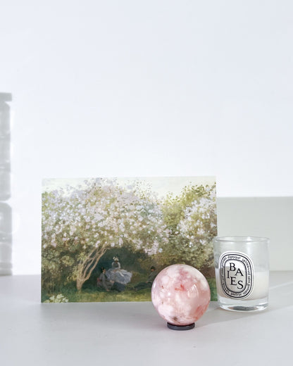 Diptyque candle, crystal ball, and artwork on a white surface