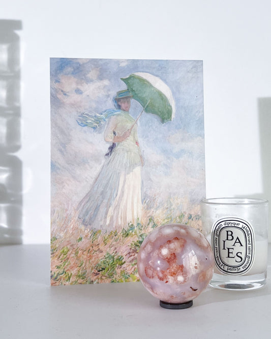 Ume Carnelian Flower Agate sphere styled with Monet artwork and Diptyque candle, featuring soft plum and apricot tones.