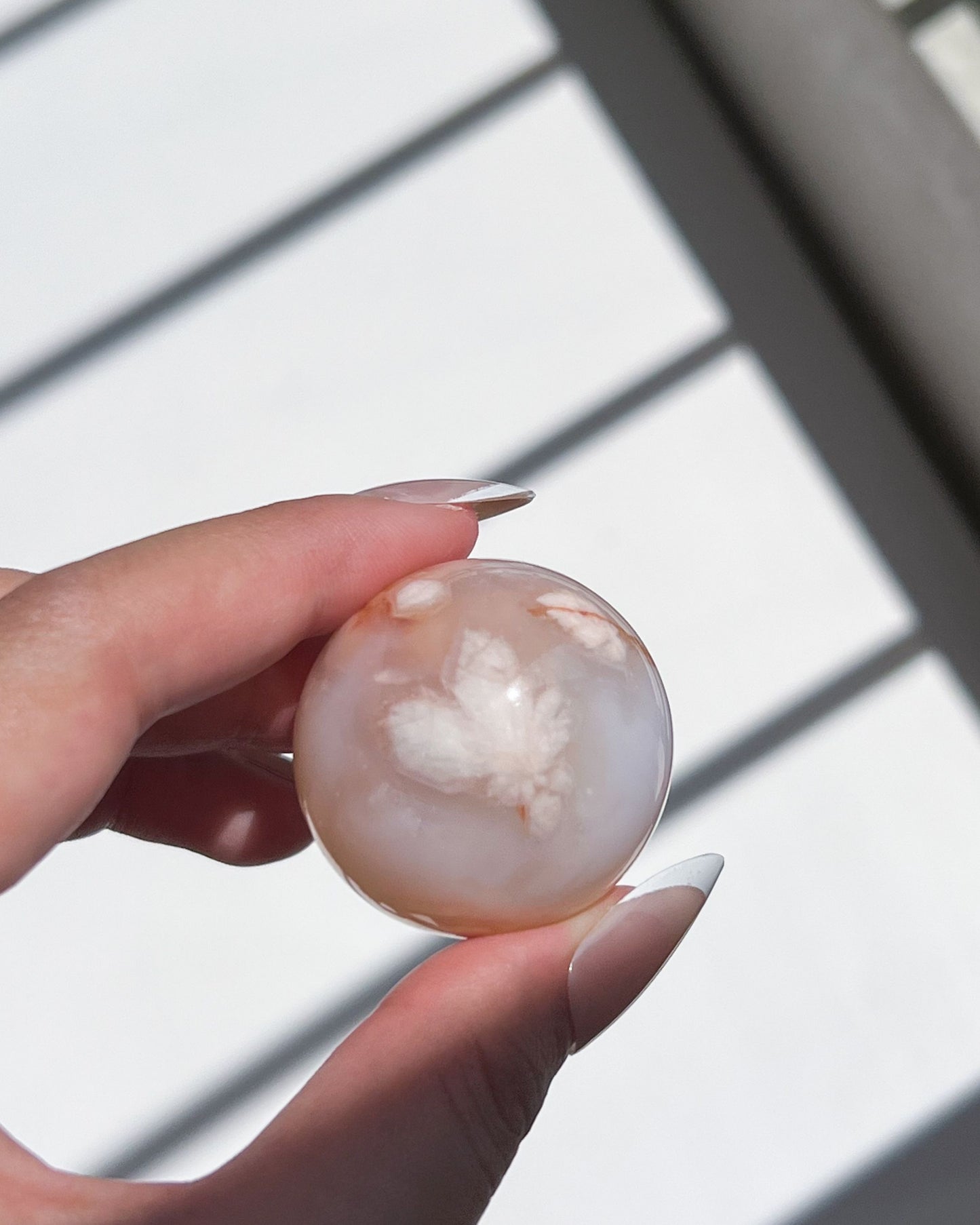 Macro shot of Sphere 07 featuring a flower-shaped white plume in the center of a translucent pink surface, reminiscent of a delicate bloom suspended in water.