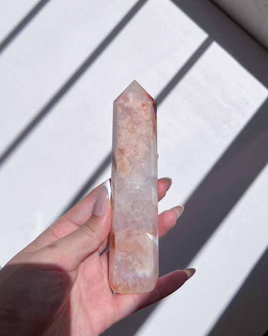Hand holding a tall Carnelian Flower Agate tower with blush pink and translucent white patterns