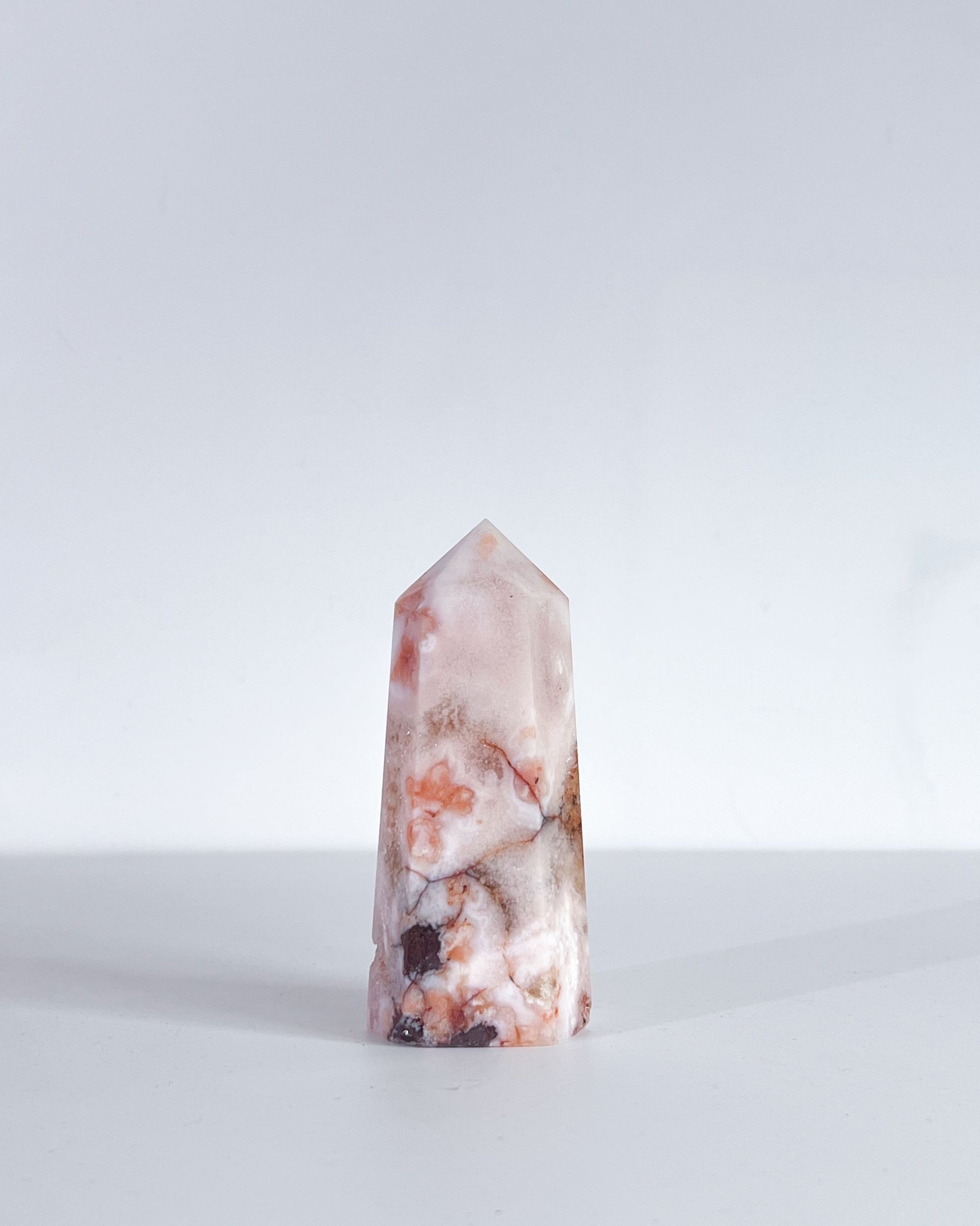 Product shot of Carnelian Flower Agate tower standing upright against white background