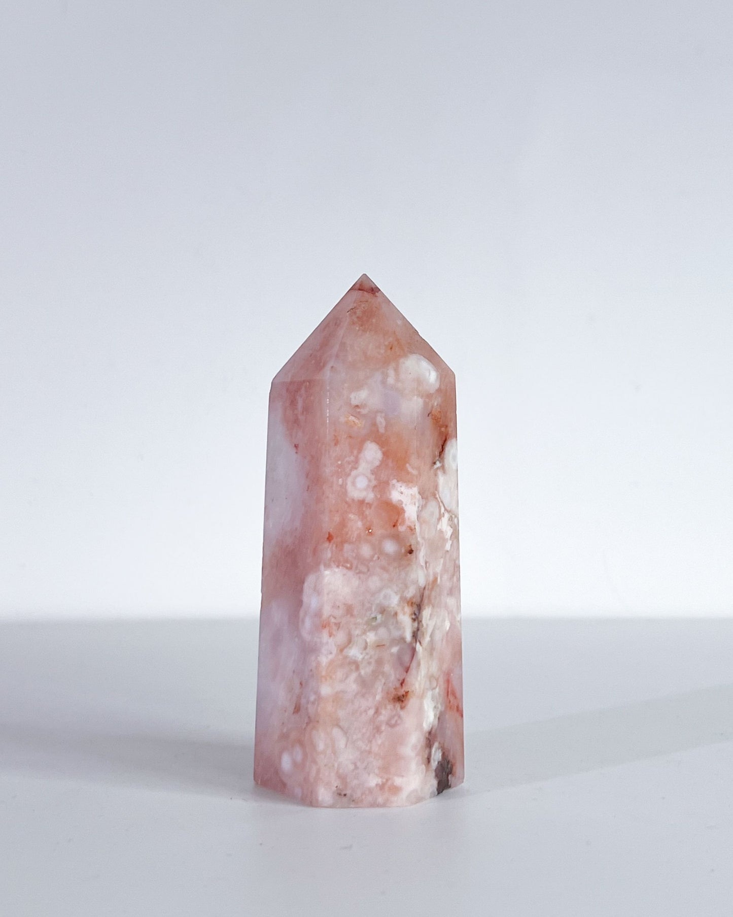 Crystal tower with pink and white coloration on a light gray background