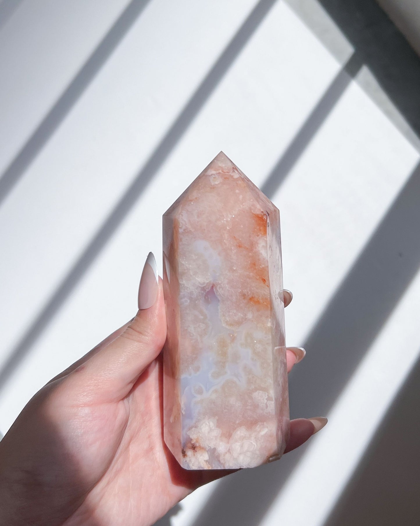 Hand holding Renoir Carnelian Flower Agate tower under daylight shadows