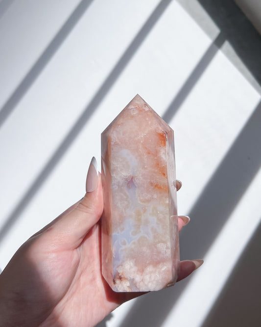 Hand holding Renoir Carnelian Flower Agate tower under daylight shadows