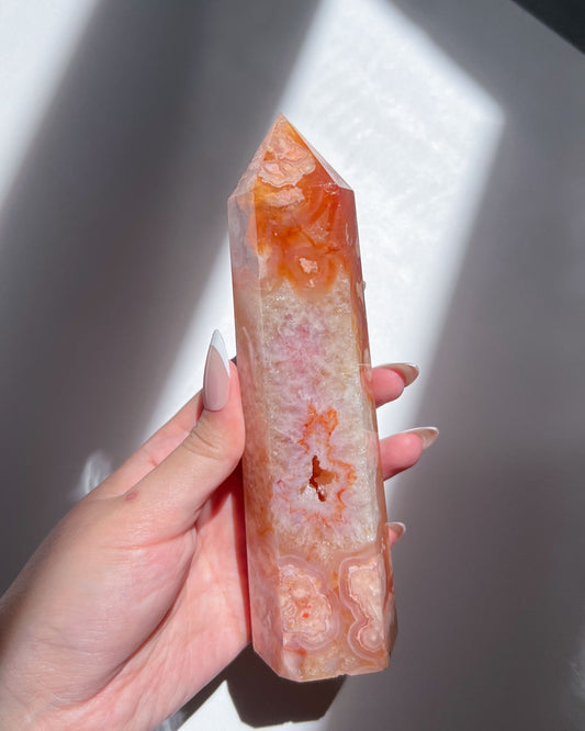 Hand holding Saffron Carnelian Flower Agate tower under soft natural light, showing vivid orange and blush floral plumes