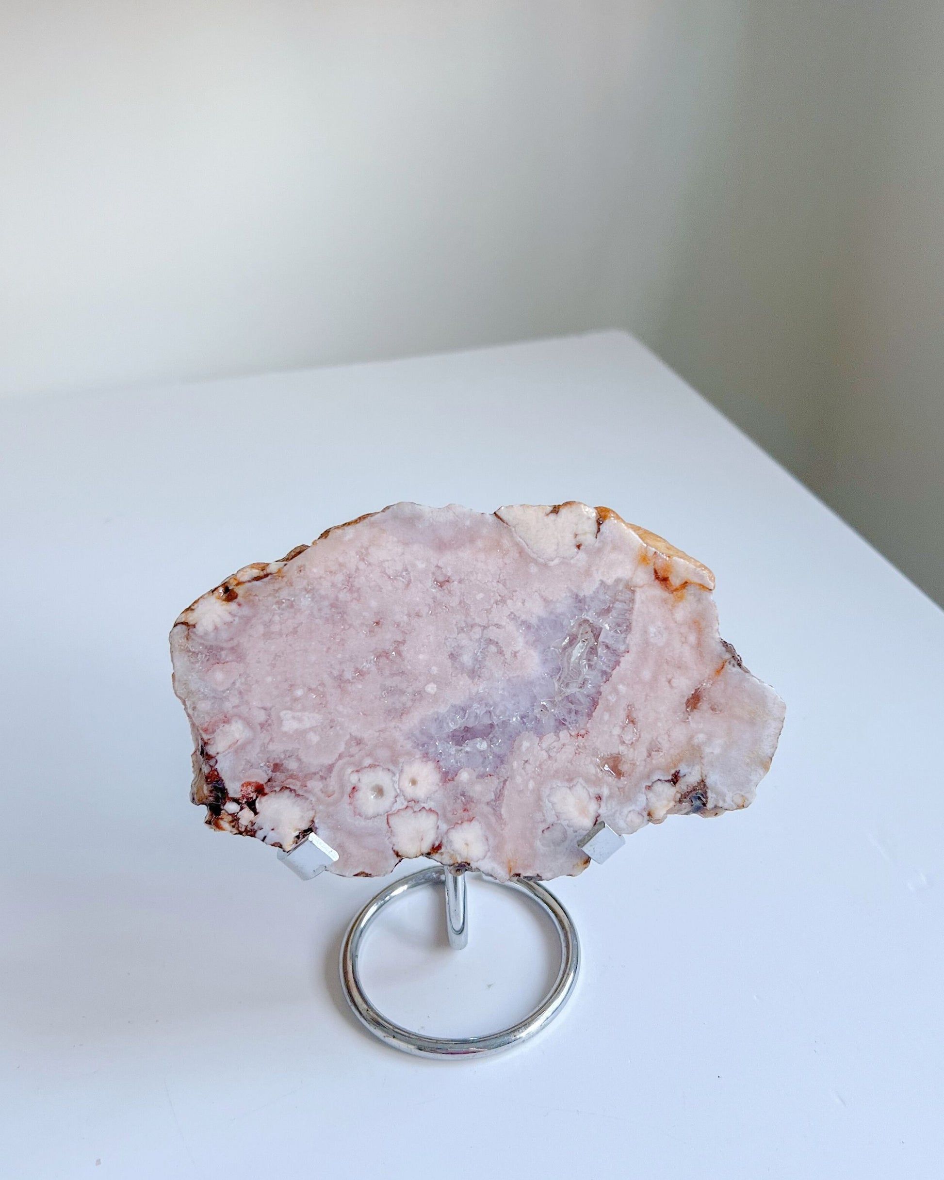 Roselle flower agate slab on a stand against a white background