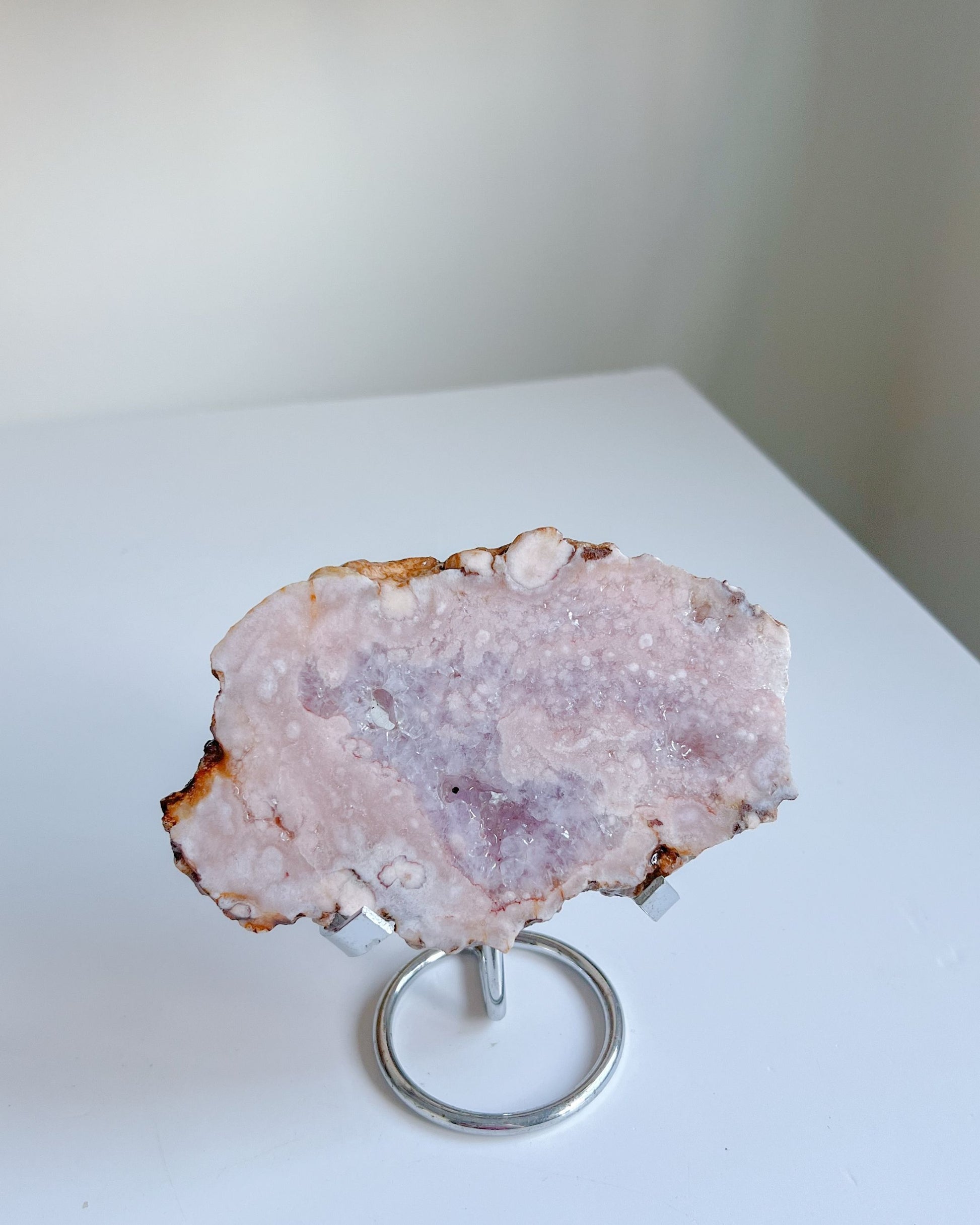 Flipside of Roselle flower agate slab on a stand against a white background