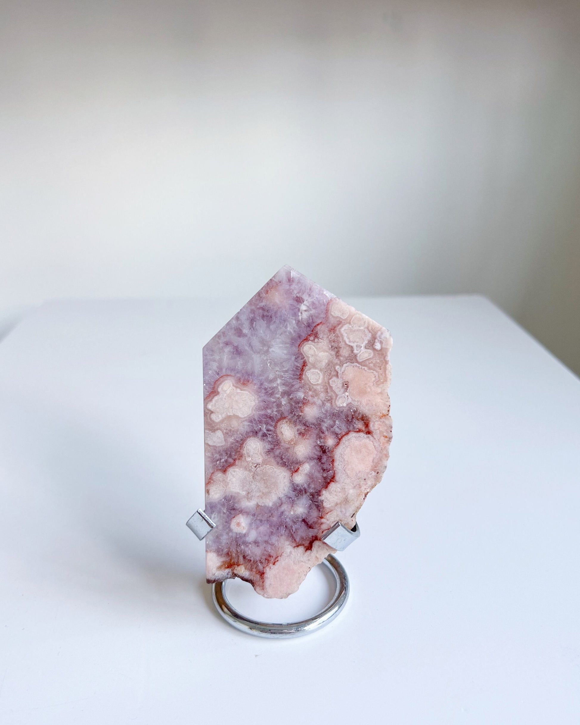 Naomi slab displayed upright in a metal stand, revealing soft orchid tones and bloom clusters