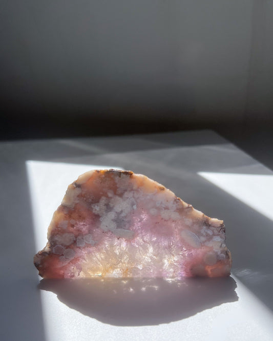 Avery Flower Agate slab on white surface with soft golden light and pink blush reflections