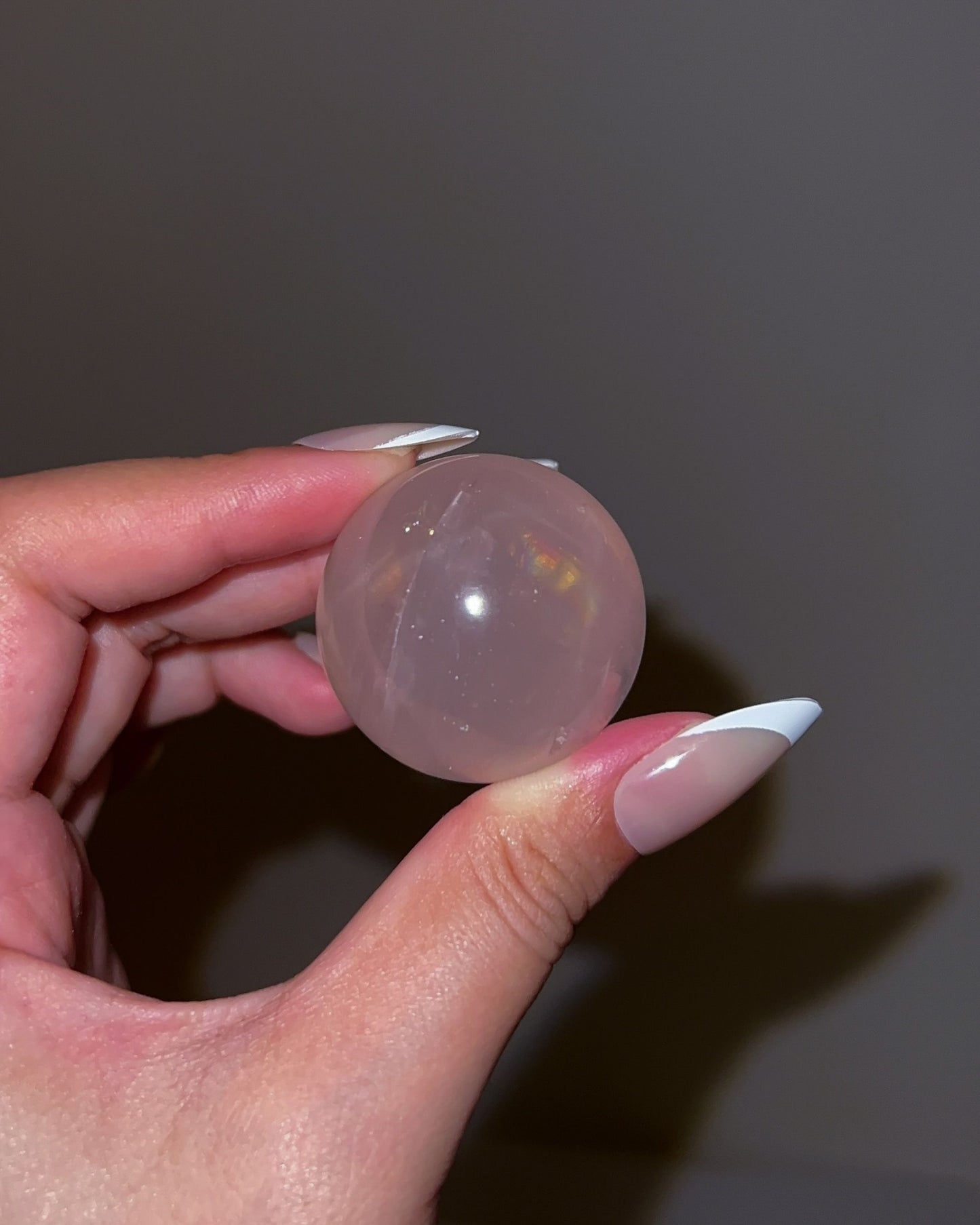 Girasol Rose Quartz sphere photographed under flash, showing a luminous sheen with subtle color play and warm pink clarity.