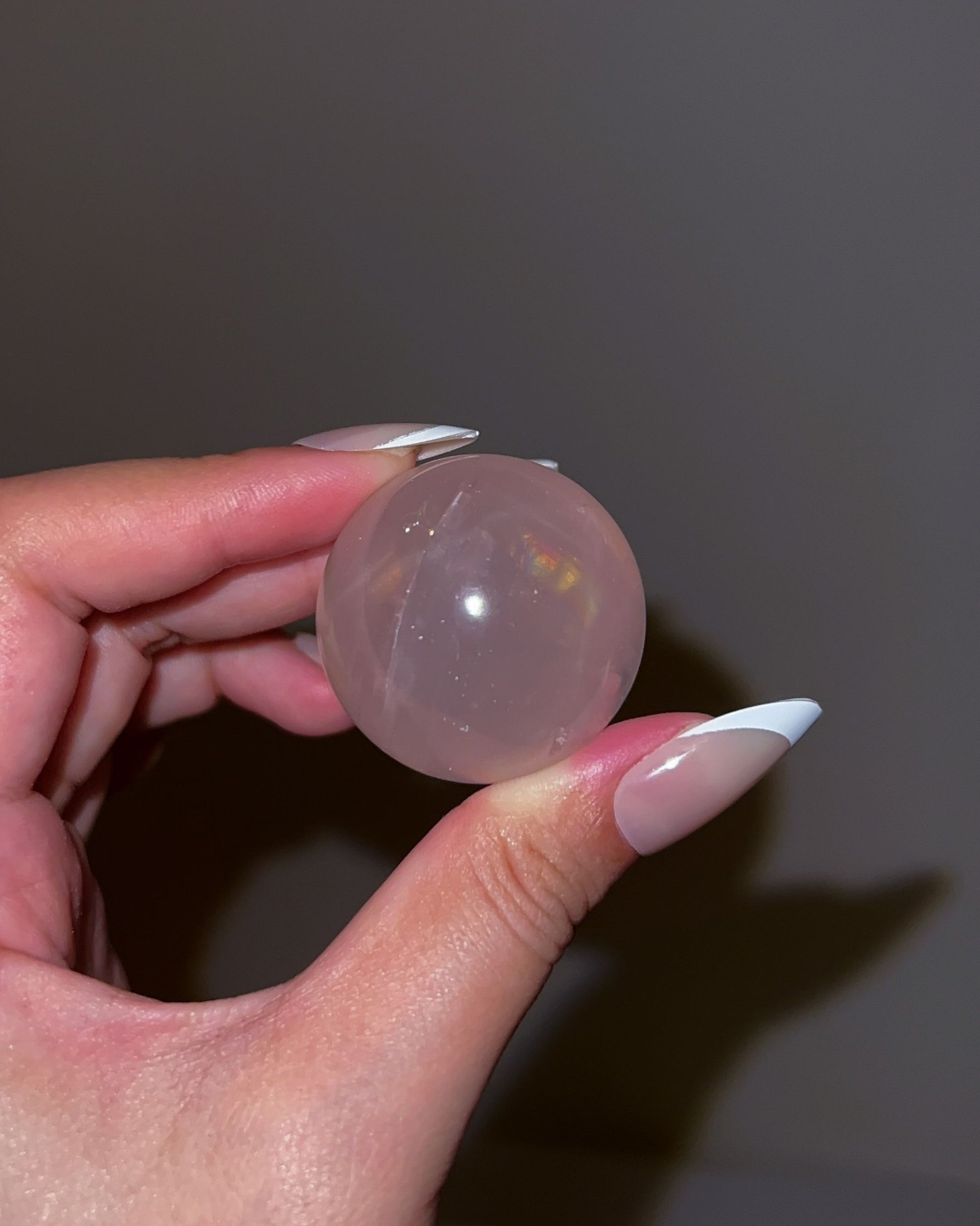 Girasol Rose Quartz sphere photographed under flash, showing a luminous sheen with subtle color play and warm pink clarity.
