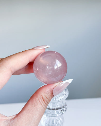 Girasol Rose Quartz Sphere H held up in daylight, capturing subtle internal wisps and dreamy transparency