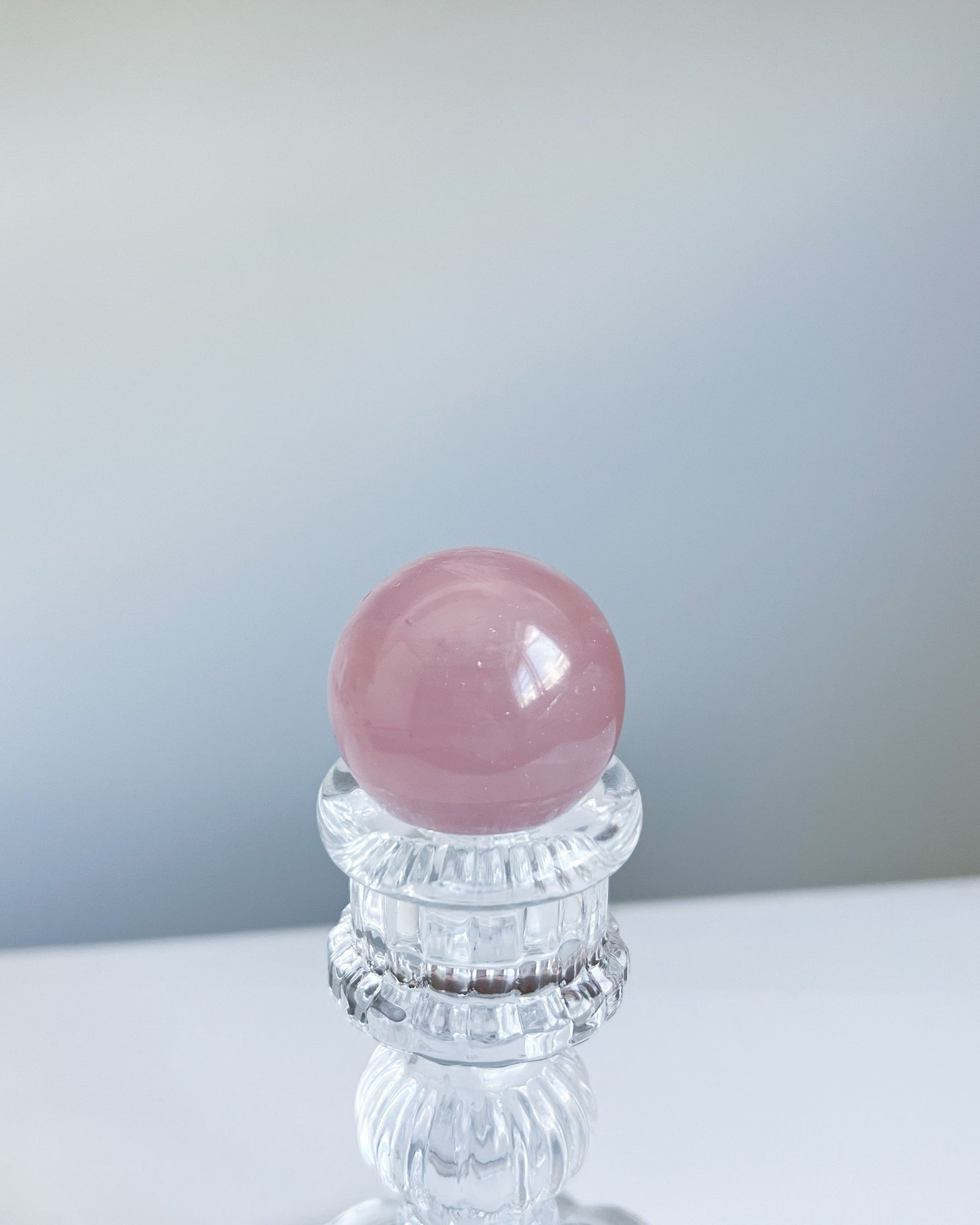 Top-down view of Girasol Rose Quartz Sphere H on a stand, emphasizing its blush hue and gentle luminescence