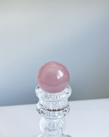 Top-down view of Girasol Rose Quartz Sphere H on a stand, emphasizing its blush hue and gentle luminescence