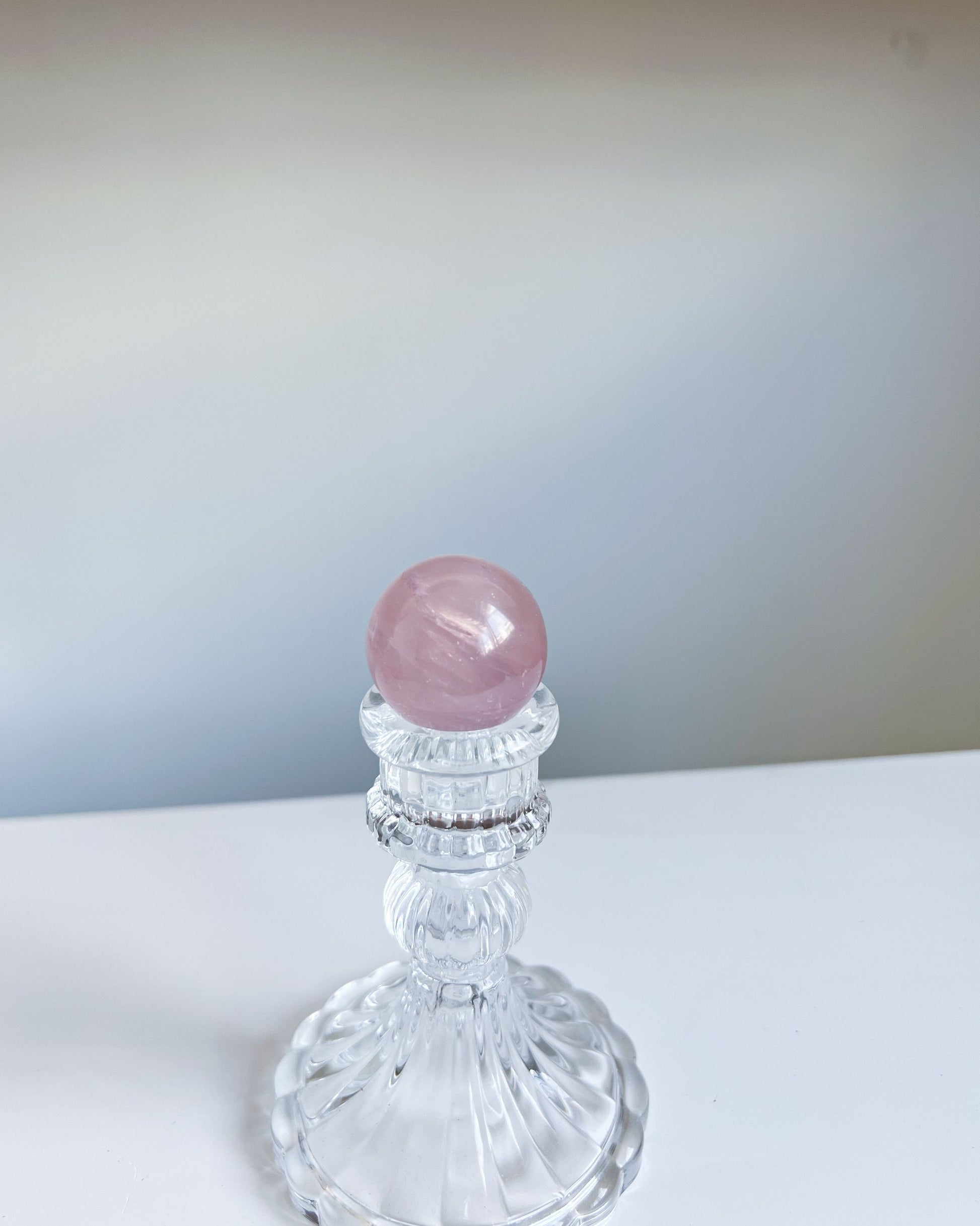 Full view of Girasol Rose Quartz Sphere H on an ornate crystal pedestal, appearing soft and ethereal