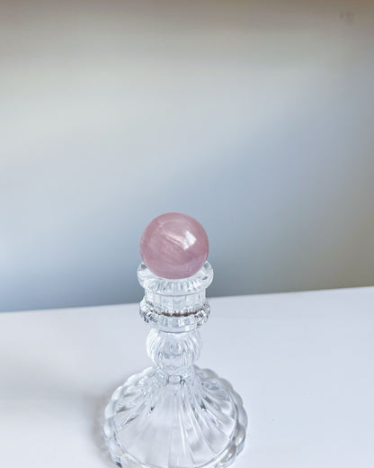 Full view of Girasol Rose Quartz Sphere H on an ornate crystal pedestal, appearing soft and ethereal