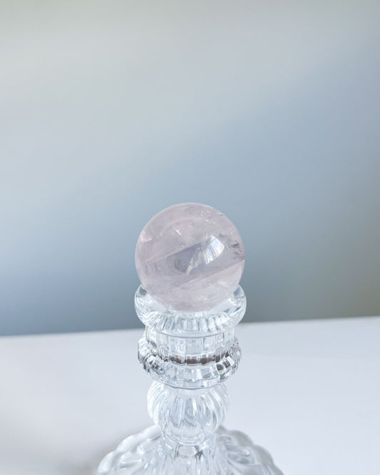 Girasol Rose Quartz Sphere I on a crystal pedestal, softly glowing with light lavender undertones