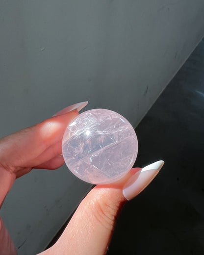 Girasol Rose Quartz Sphere I held under direct sunlight, showing intricate internal clarity and layered textures