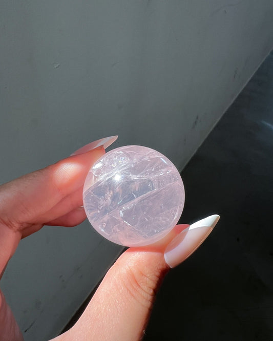 Girasol Rose Quartz Sphere I held under direct sunlight, showing intricate internal clarity and layered textures